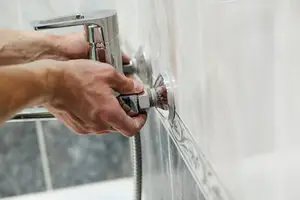 Hands turning faucet knobs which are in need of Rochester residential plumbing services