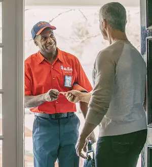 Mr. Rooter plumber handing a customer a business card