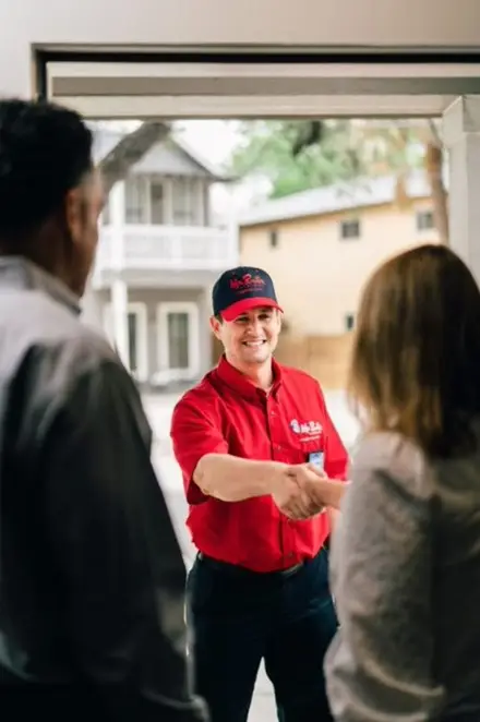 Male Mr. Rooter plumber in branded red polo shirt greeting customers.
