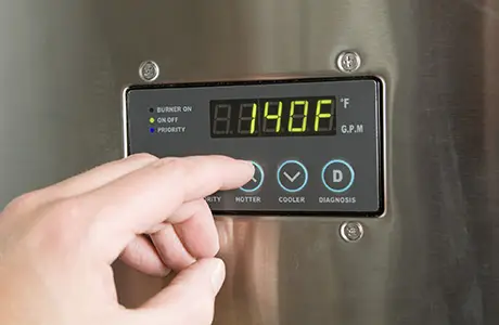 Hand touching tankless water heater after a water heater repair