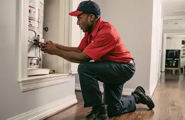 Mr. Rooter plumber servicing a water heater inside of a home
