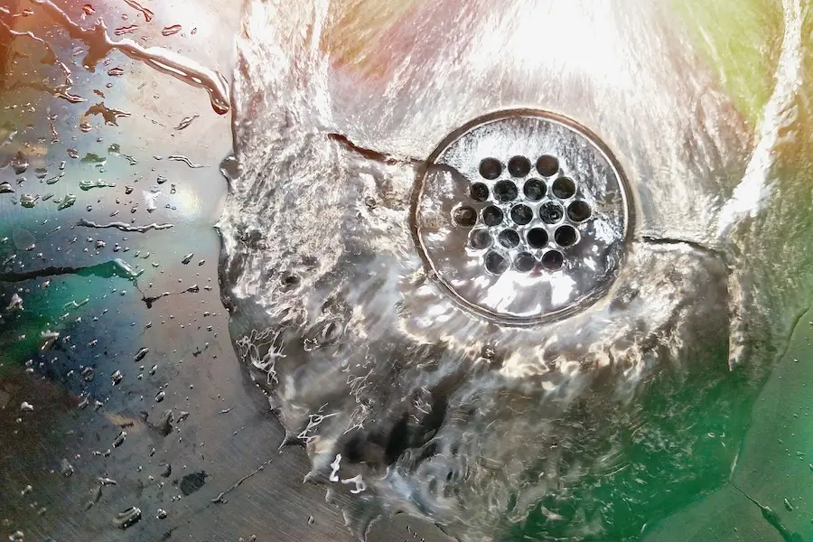 Water swirling and draining through a round metal sink drain.