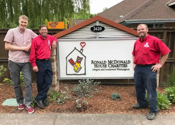 RMHC Director of Building Operations Andy Olds, with Mr. Rooter Plumbing employees Brian Buelt and Jim McDonald beside remodeled RMHC sign.